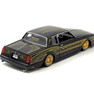 1986 Chevrolet Monte Carlo SS Lowrider Black Metallic with Gold Graphics and Wheels "Lowriders" Series 1/24 Diecast Model Car by Maisto